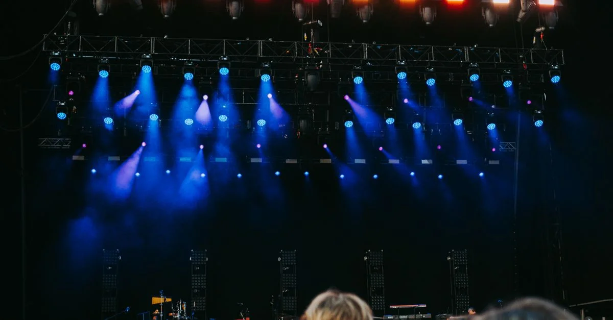 Scène de concert nocturne avec public, scène et effets d'éclairage colorés.