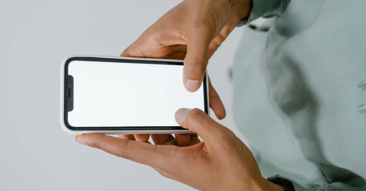 Mains tenant un smartphone avec un écran vierge, parfait pour des maquettes ou un espace de texte.