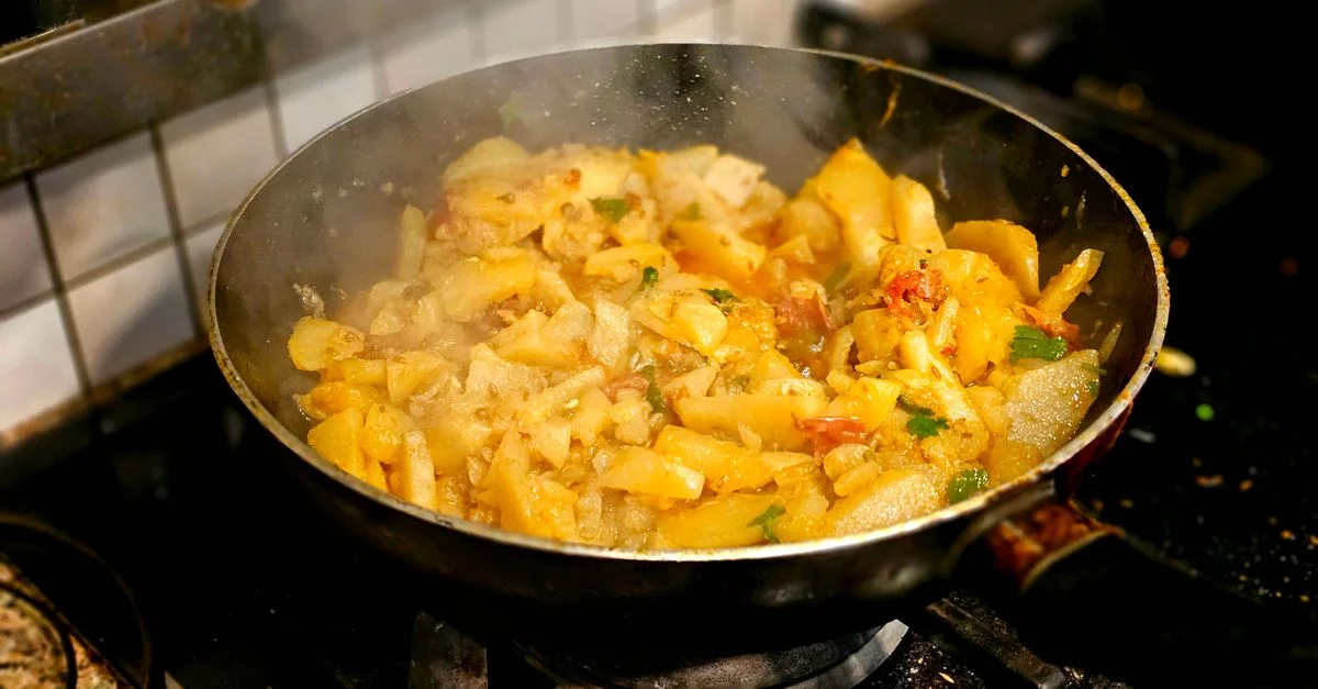 Un délicieux sauté de pommes de terre cuisiné dans une poêle avec de la vapeur qui s'échappe.