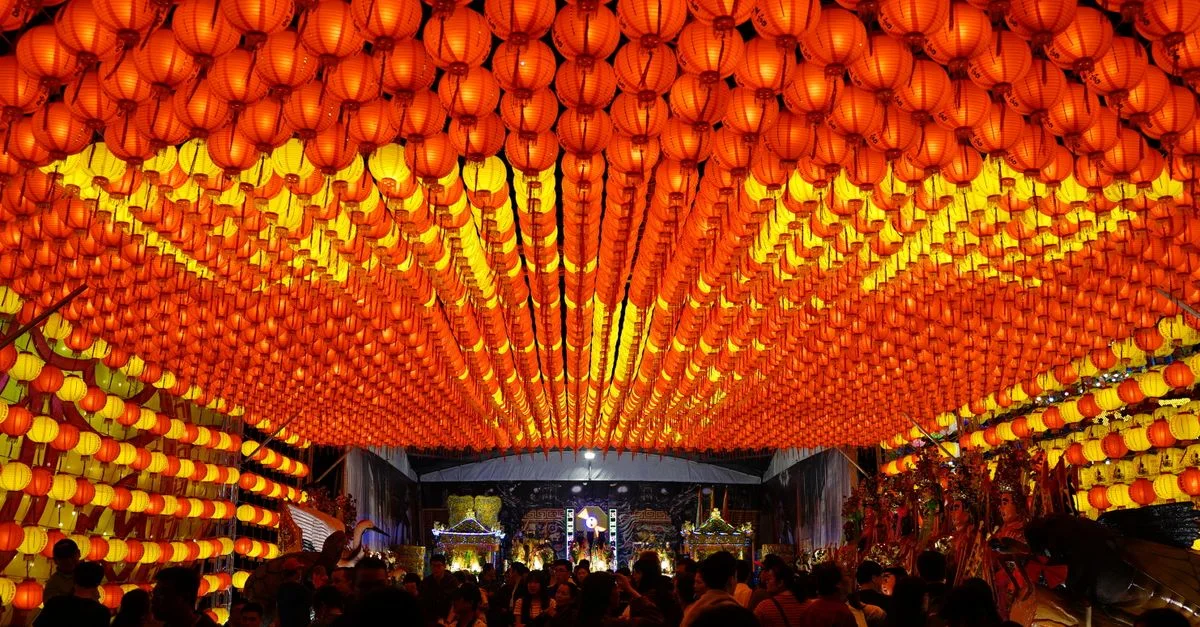 Une scène de festival animée à Taïwan avec des lanternes rouges traditionnelles illuminant une célébration nocturne.