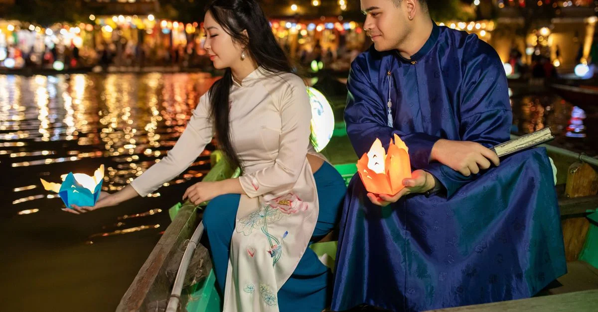 Un couple lâche des lanternes la nuit, le long du fleuve, à Hoi An, au Vietnam.